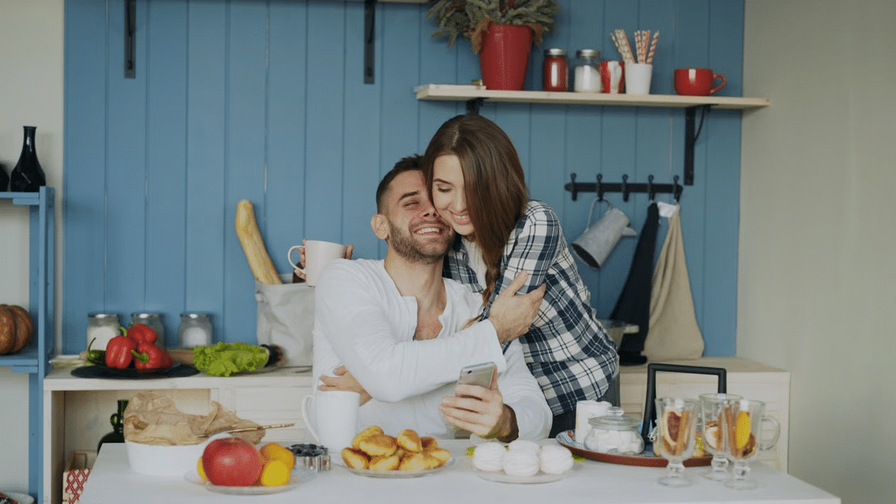 A man does the laundry as he talks cheerfully to his wife.