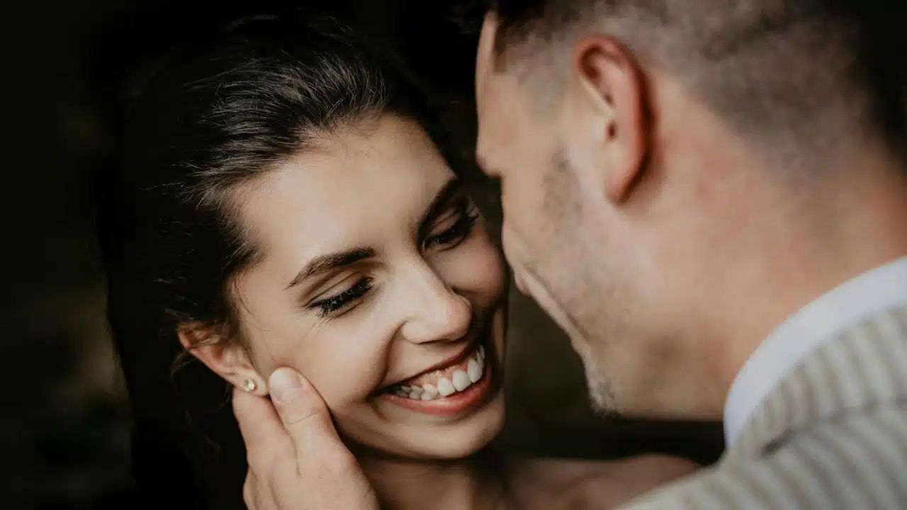 A man and woman smiling while standing close to each other.