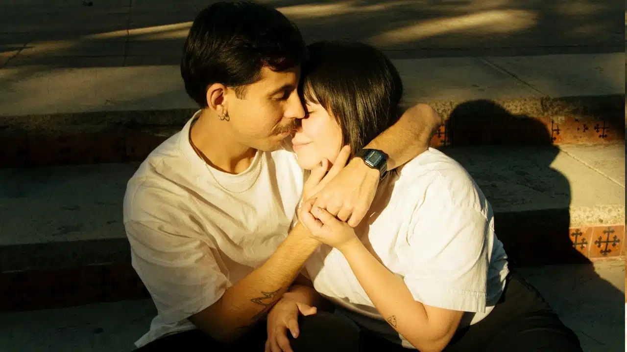 A man and a woman hugging each other while they are sitting on the stairs.