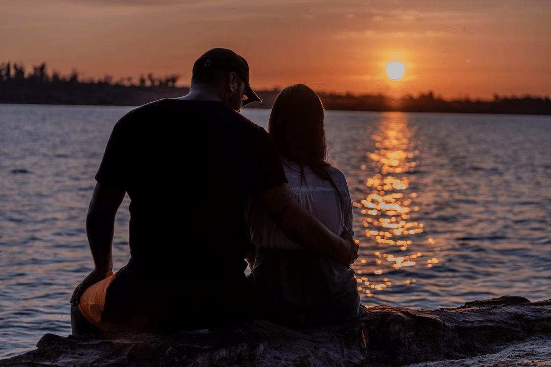 A man and a woman sitting on seaside quietly.