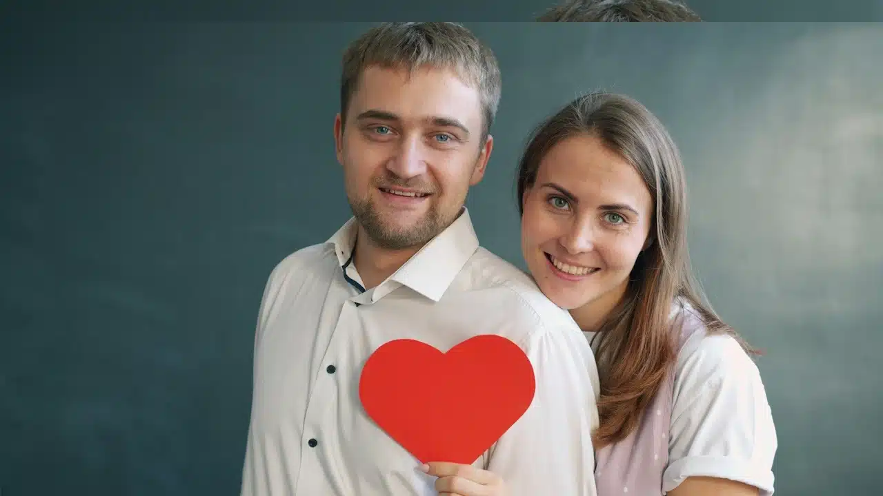 A Couple holding a red heart symbol.