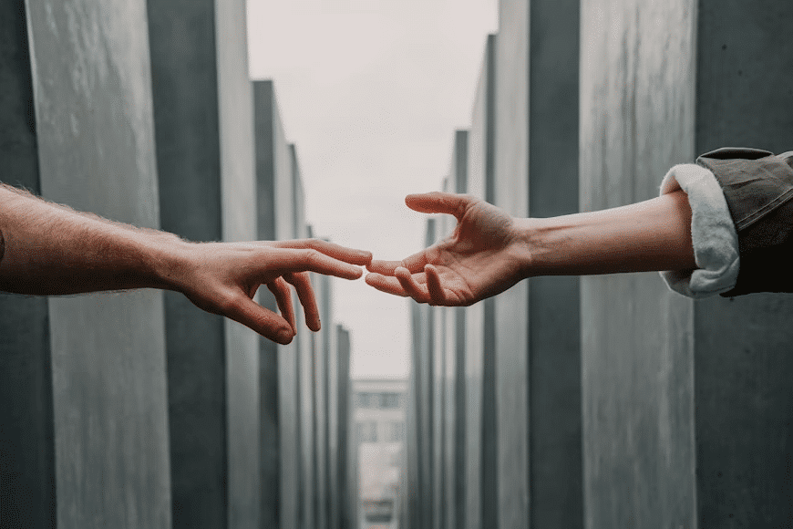 Two hands reaching for each other but barely connected.