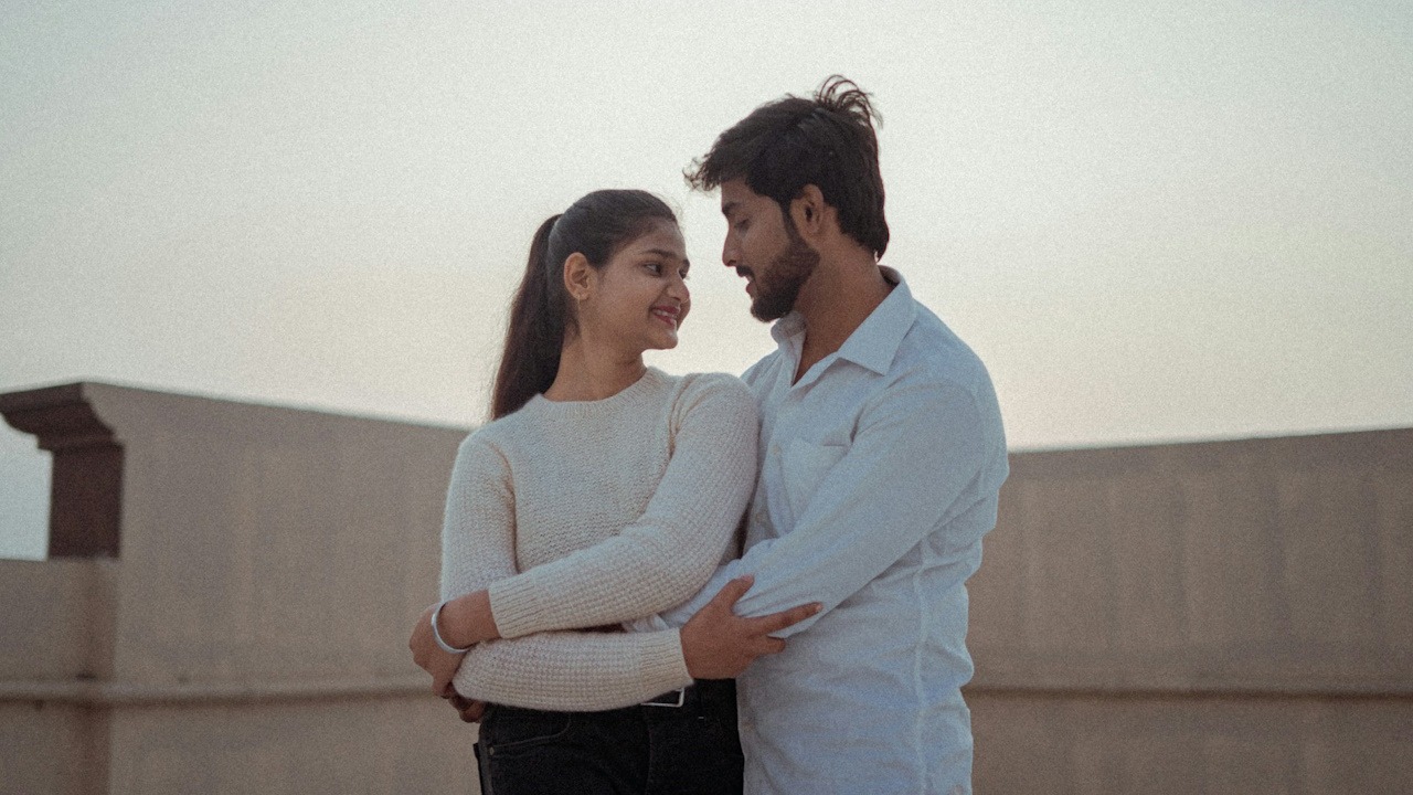 A couple hugging each other while standing on the rooftop of their home.