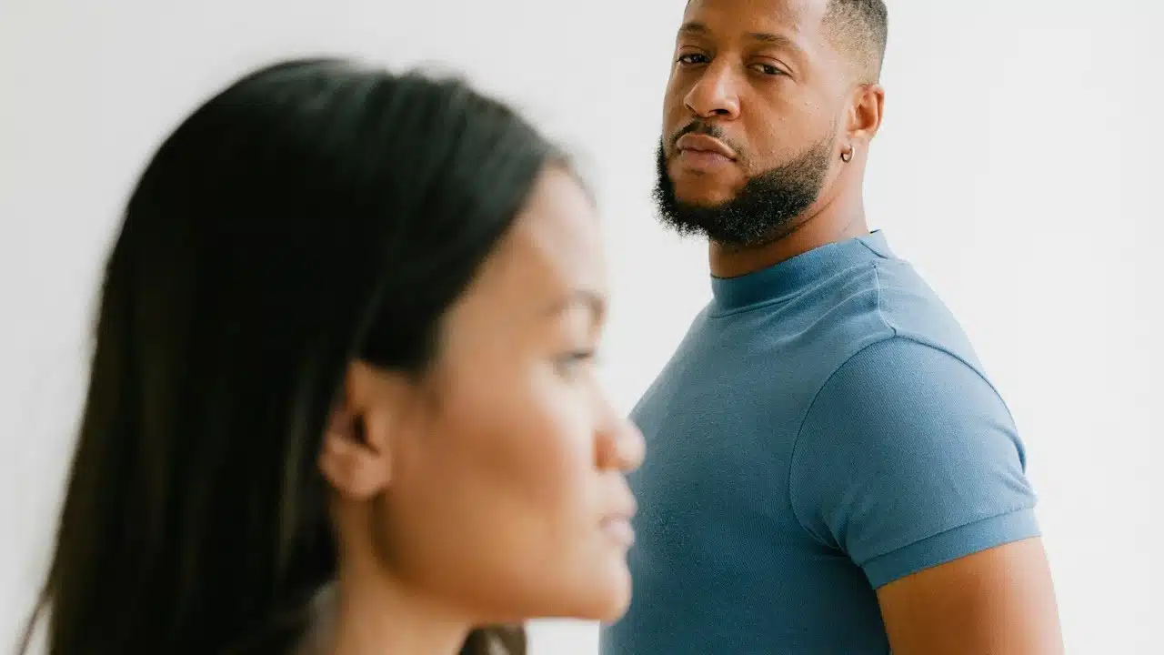 A bearded man looking at a woman who stares straight ahead.