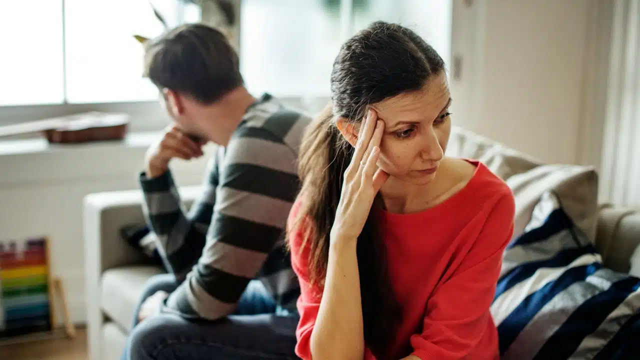 A frustrated couple sitting on a couch after having an argument.