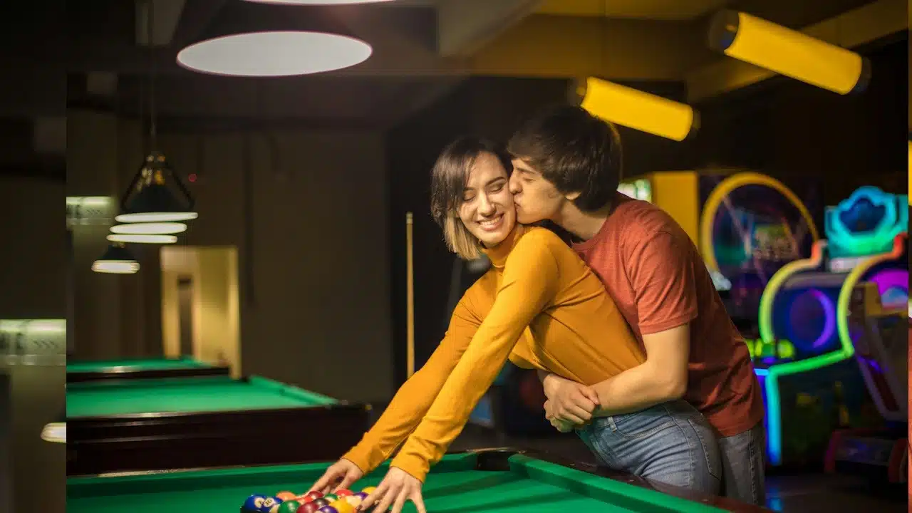 A couple is kissing in the billiard room.