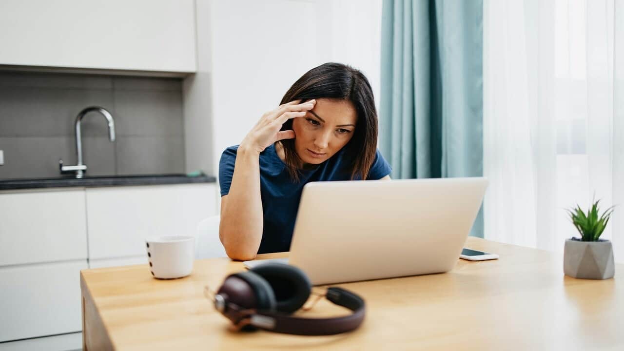 A woman looking at her laptop confused