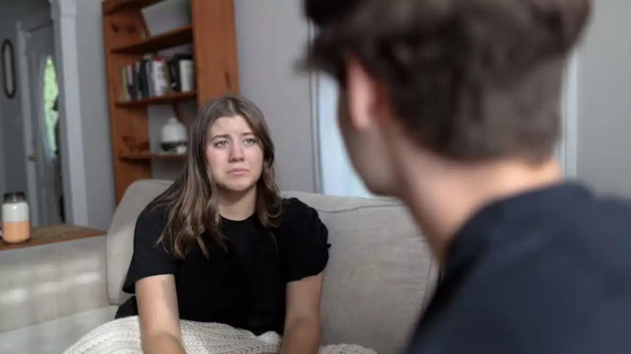 Woman looking down sadly while partner scolds her