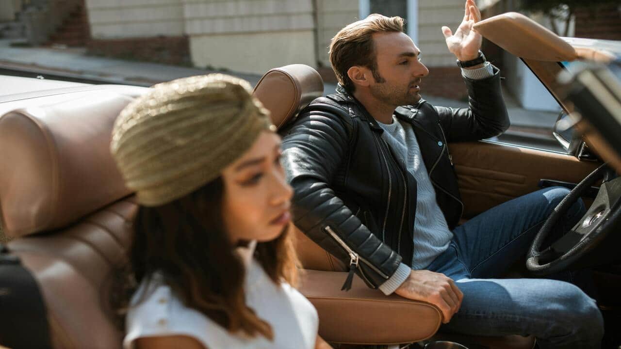 A couple arguing in a convertible car.