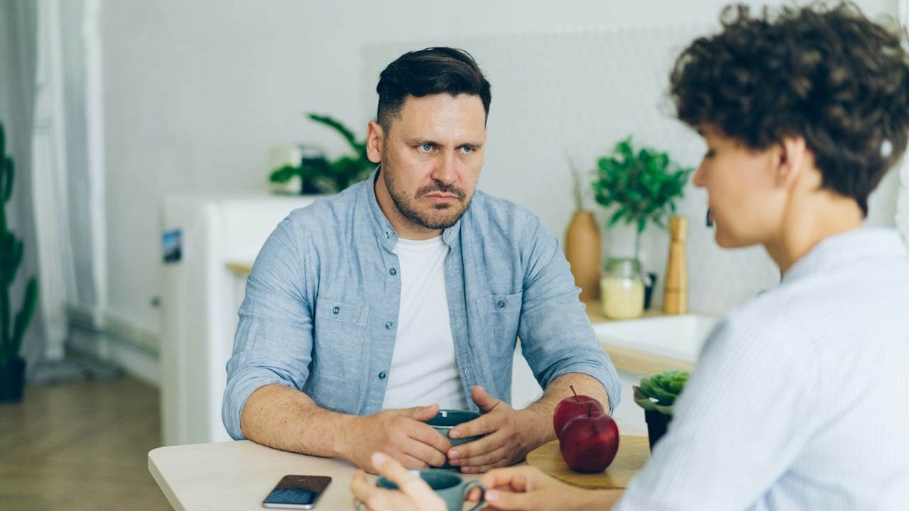 A couple arguing with each other while sitting at a table.