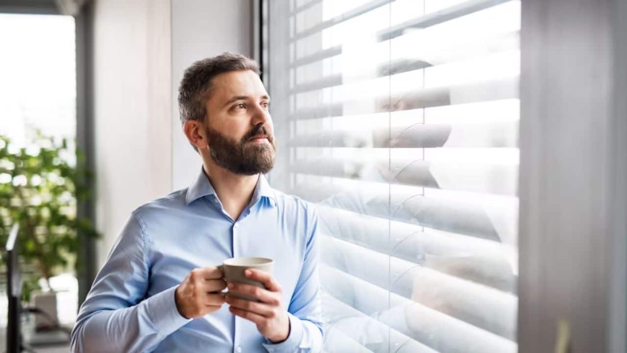 Man standing quietly, deep in thought, looking out a window