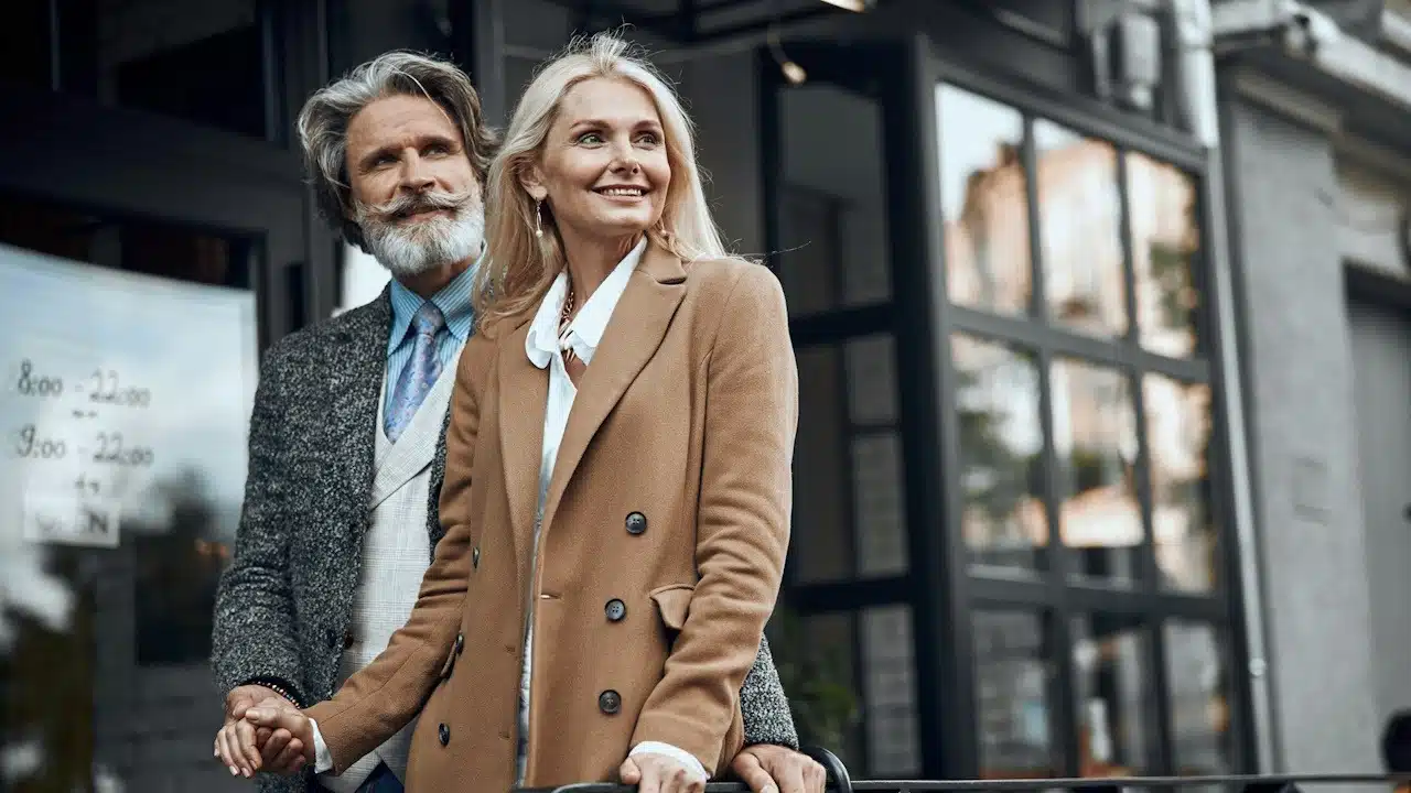 A mature couple standing in front of a cafe.