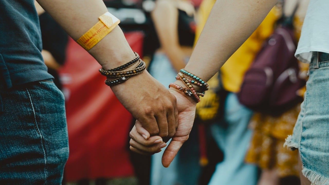 A man and a woman holding hands in a crowd.