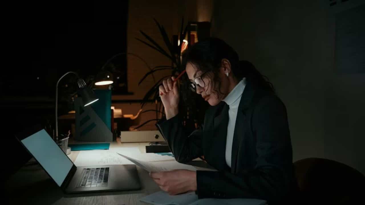 A wife working on a laptop in another room to avoid being with her husband