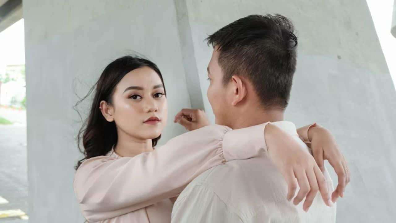 A man reaching for his wife while she gently pulls back, showing emotional distance