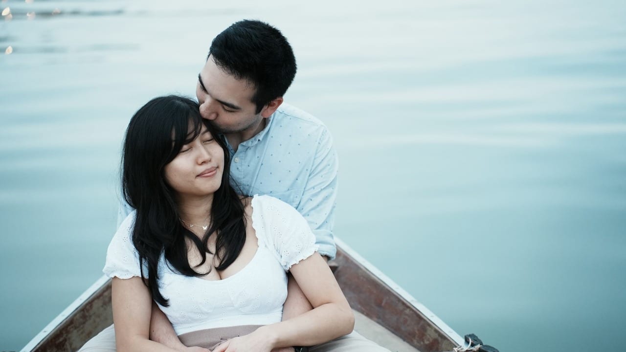 Couple embracing in a small boat, with the man kissing the woman's head.