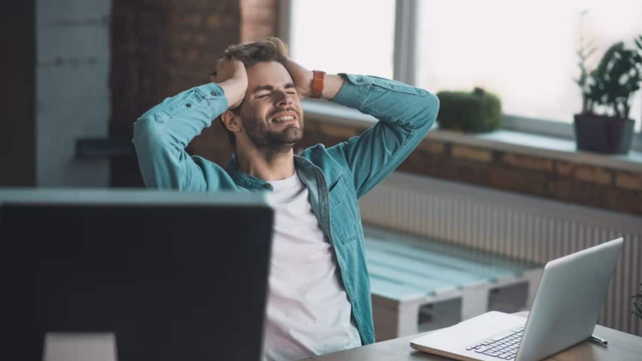 A man in casual clothes working at a desk, stressed expression