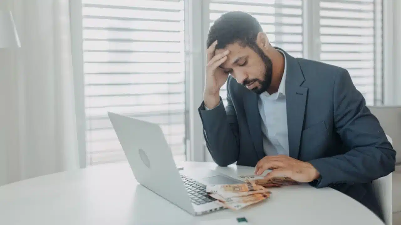 Man looking stressed while reviewing finances on laptop