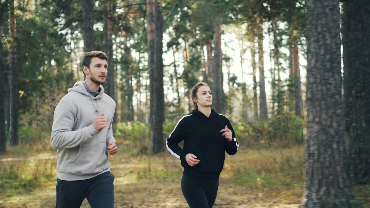 A couple jogging together in the woods.