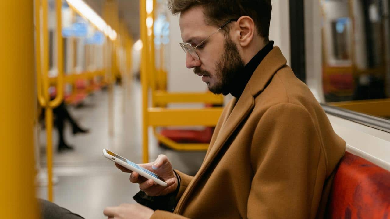 A man using his phone on a subway train.