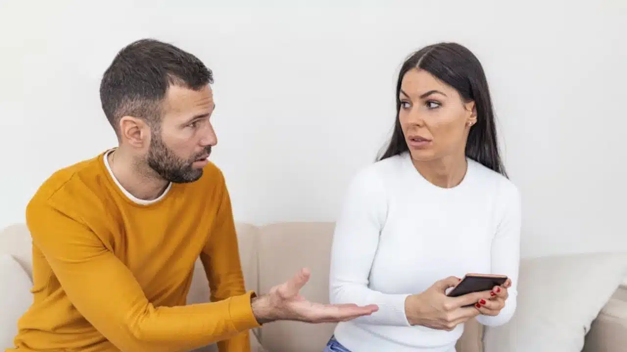 Woman sitting calmly while her partner speaks defensively