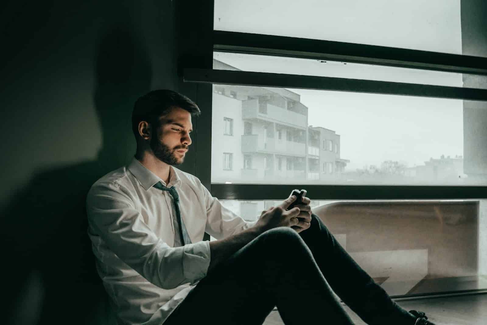 A man sitting near a window looking lonely.