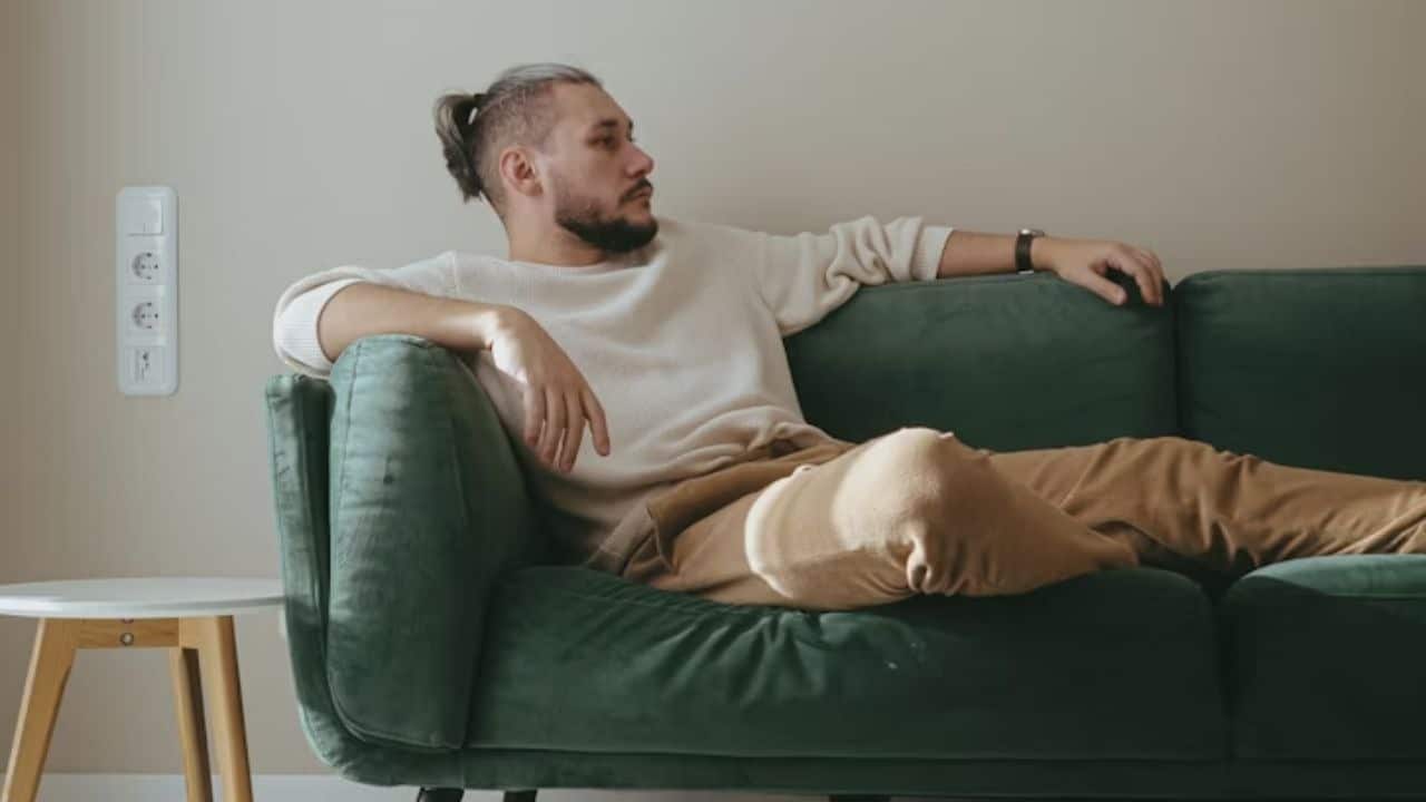 Man sitting alone on a couch with a distant look