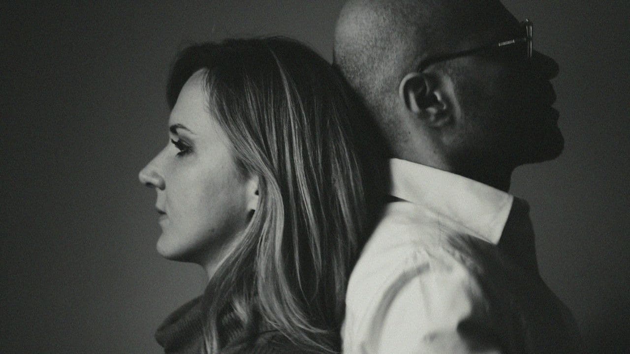 A black and white profile photo of a woman and man leaning back to back.
