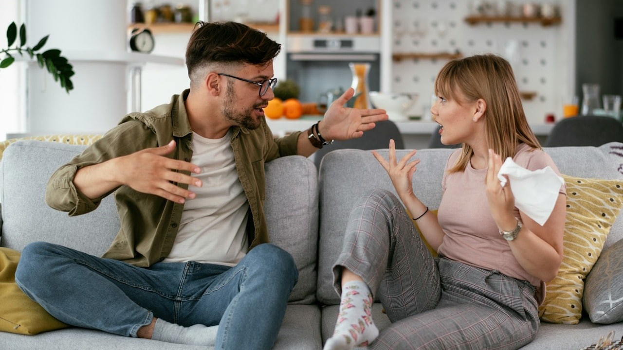 A man and a woman arguing while sitting on a couch.