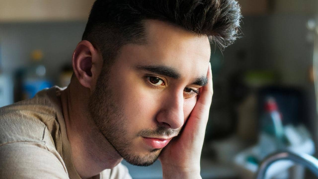 A man resting his head on his hand, looking tired and pensive.