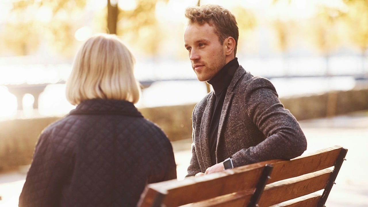 A couple sitting on a bech and talking.