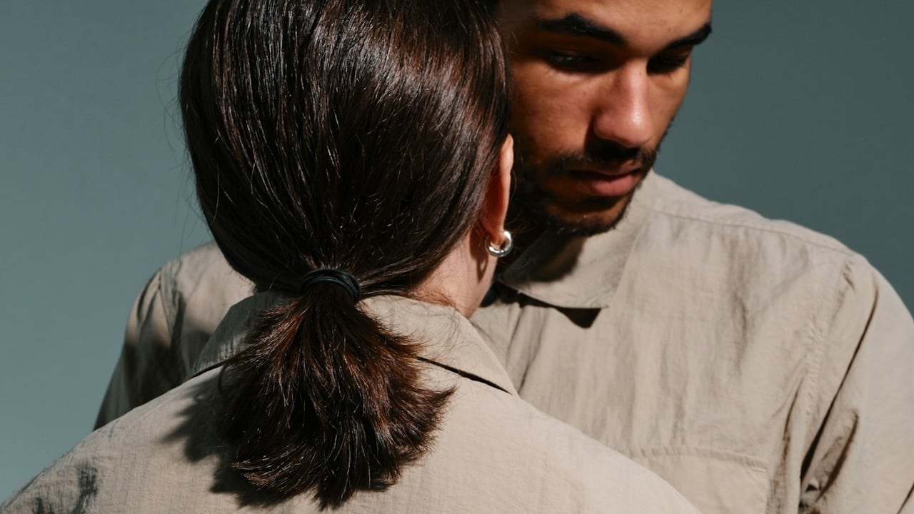 A bearded man looking down while a woman looks at him.