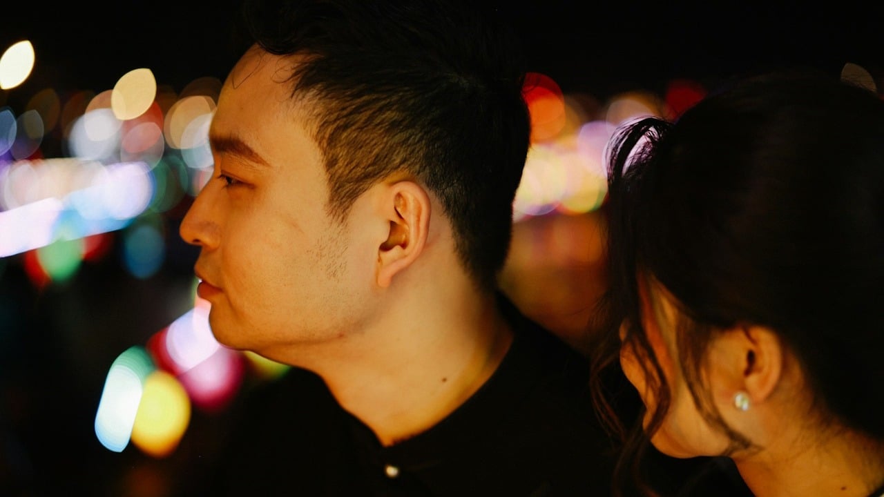 A man looking to the side while a woman looks at him.