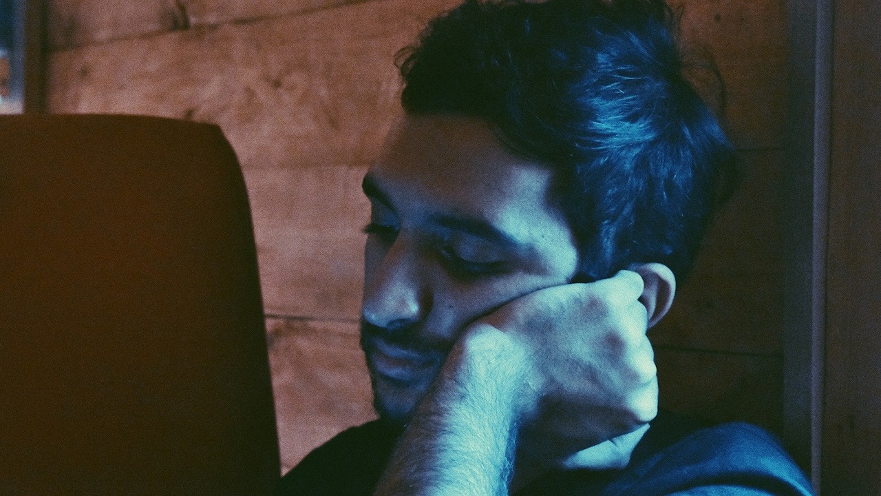 A man leaning his face on his left hand.