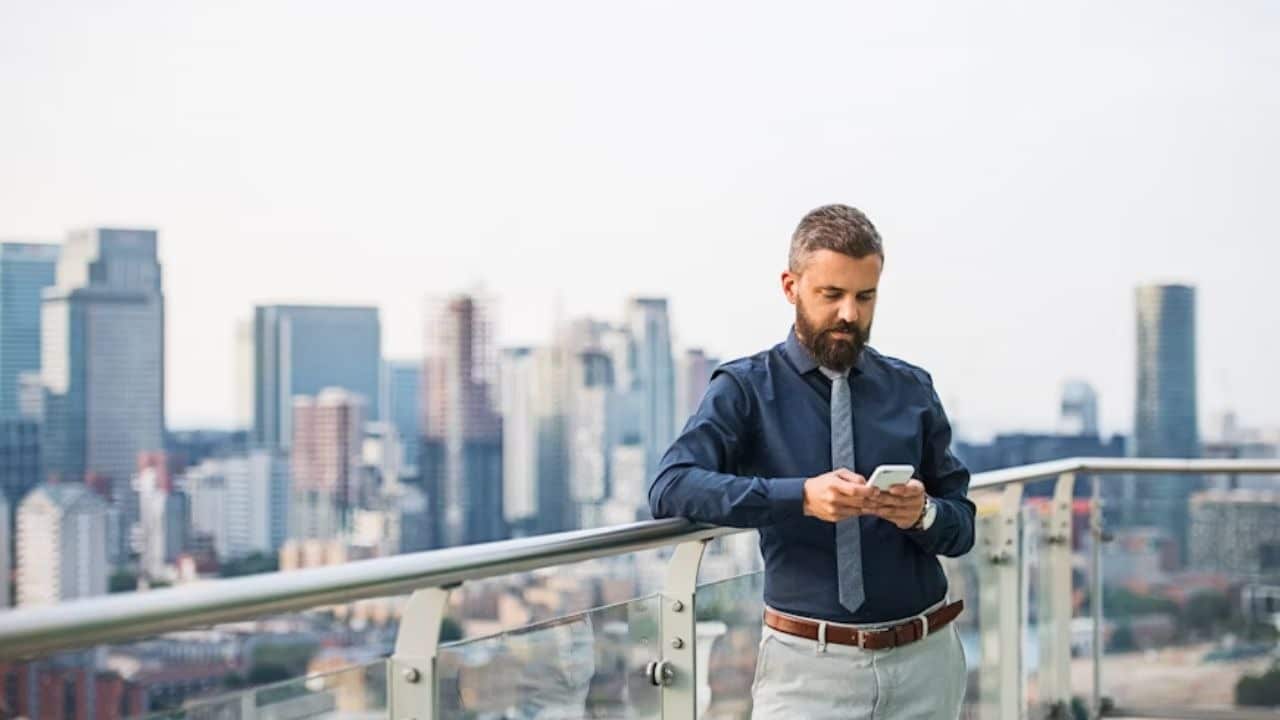 A man looking at his phone, deciding whether to reply.