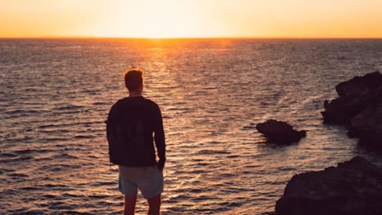 Man walking alone at sunrise by the beach
