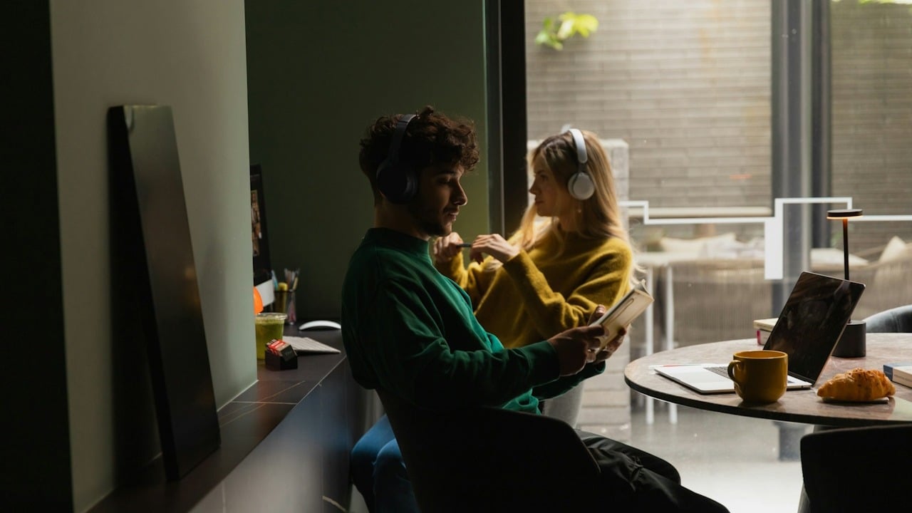 A man and a woman wearing headphones sitting separately in a room.