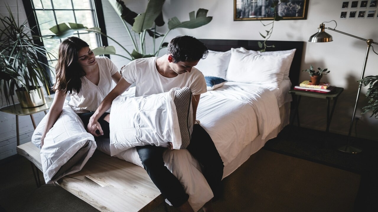 A couple ignoring each other at the foot of the bed