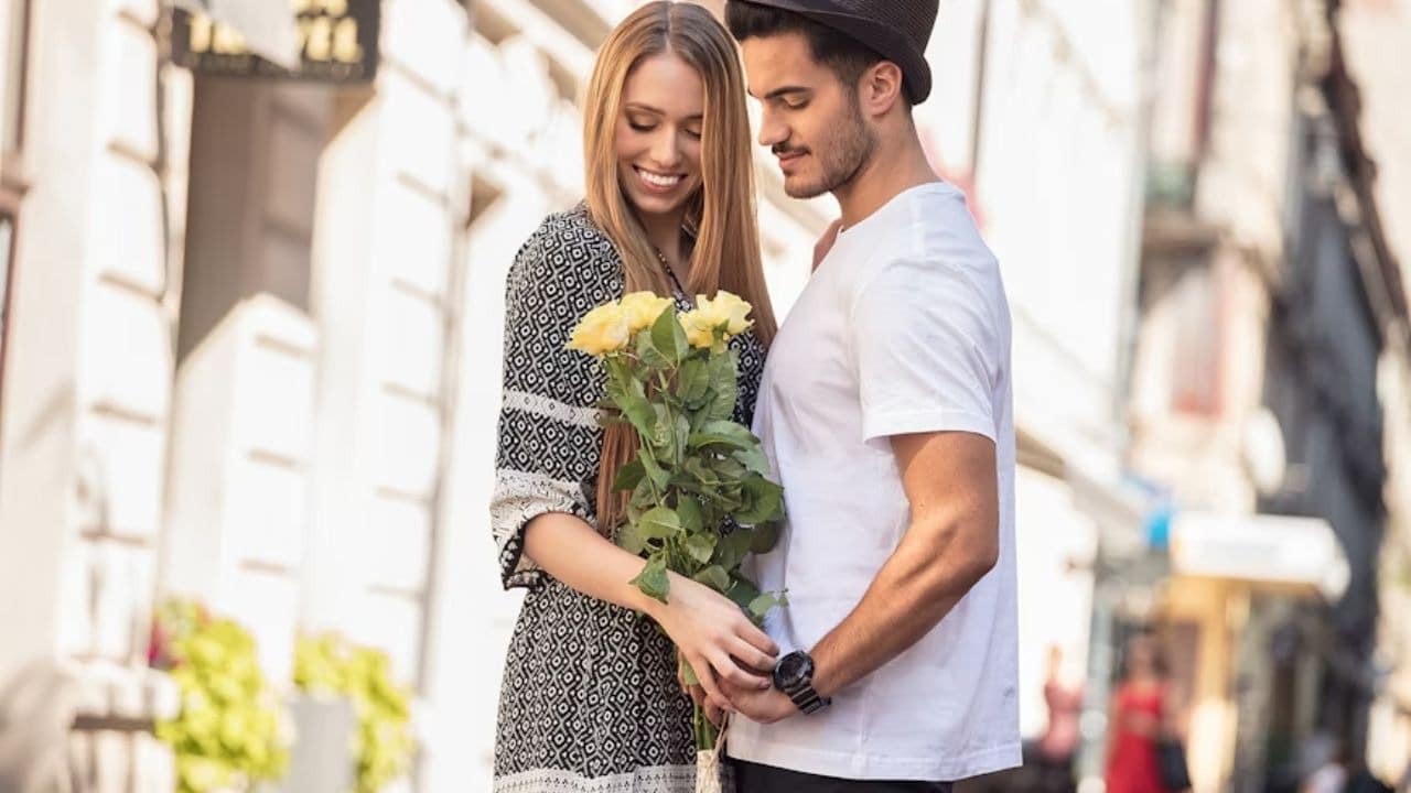 Man smiling while giving his partner flowers