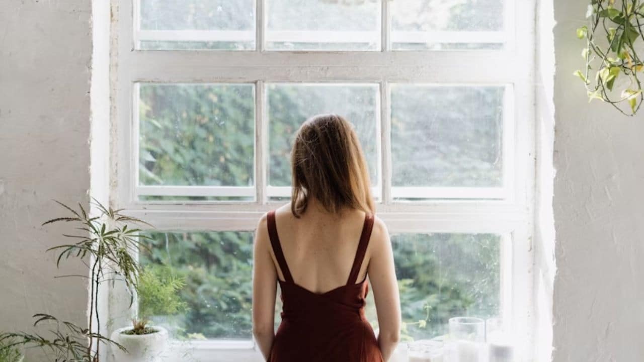 Woman looking out a window feeling empty