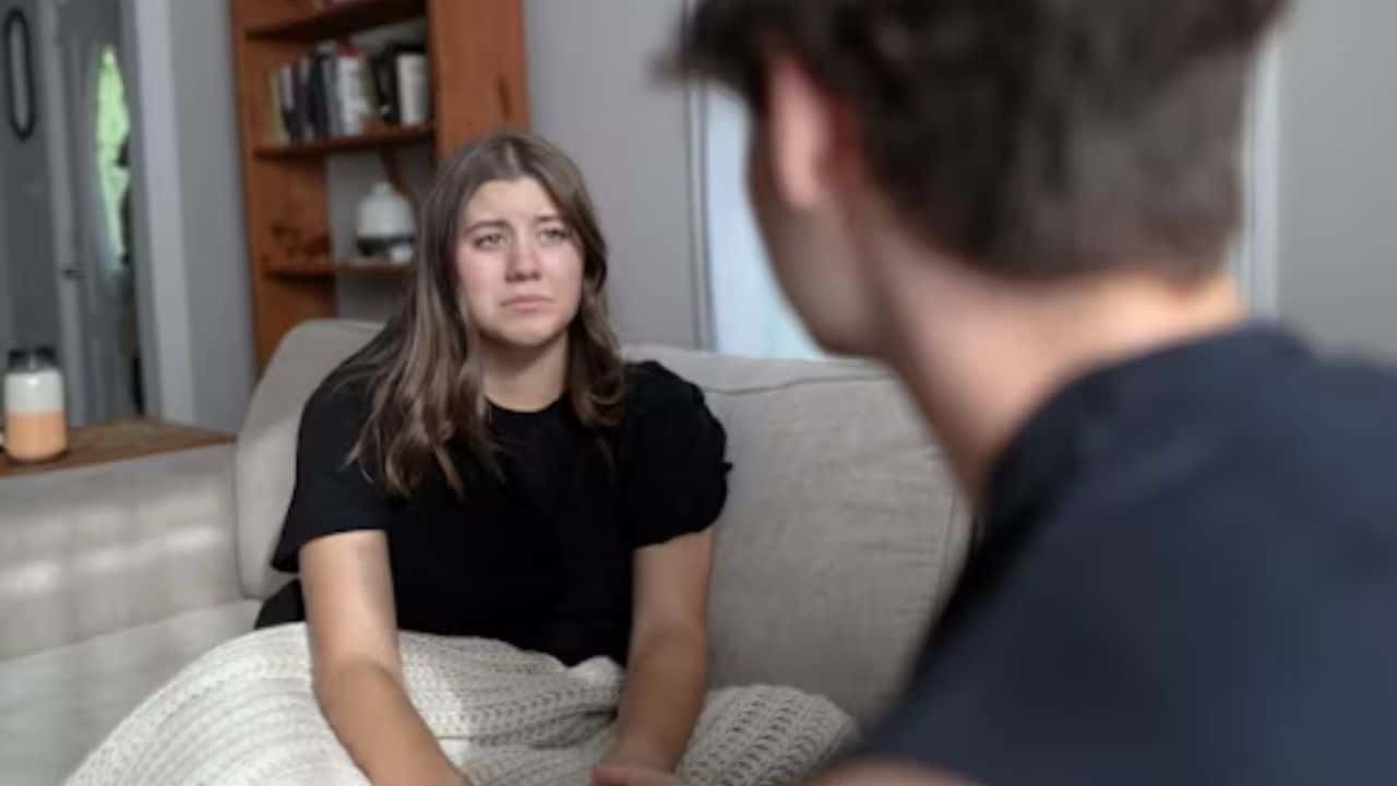 A couple sitting close, woman opening up emotionally