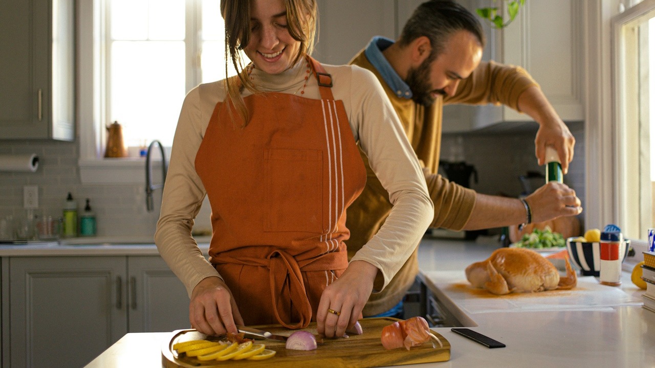 A man helping his wife out while they cook in a kitchen.