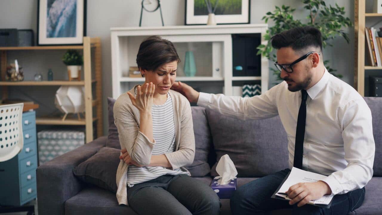 A man gesturing exasperatedly at a woman who looks upset or bored.