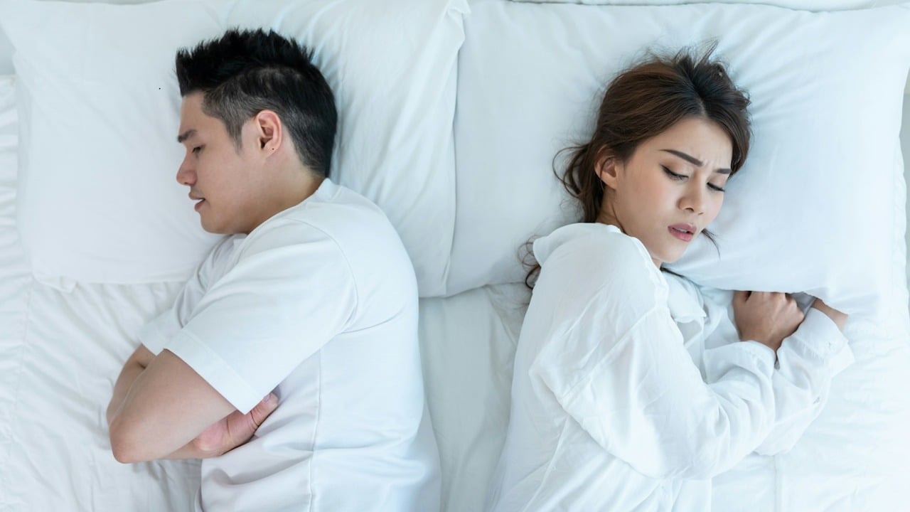 A woman feels heartbroken for their quarrel, conflict, and the man sleeping facing away from her.