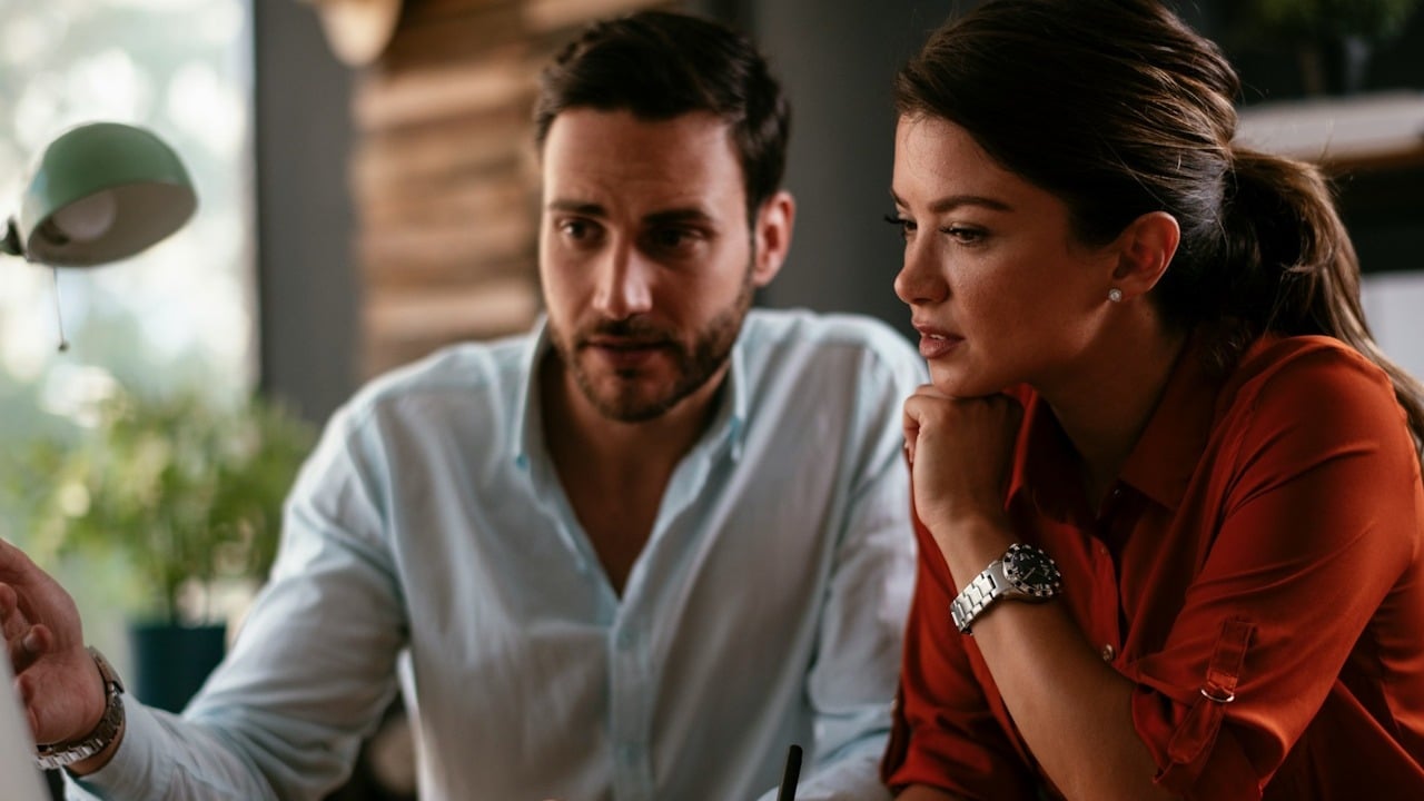 A couple looking at a screen and discussing something.