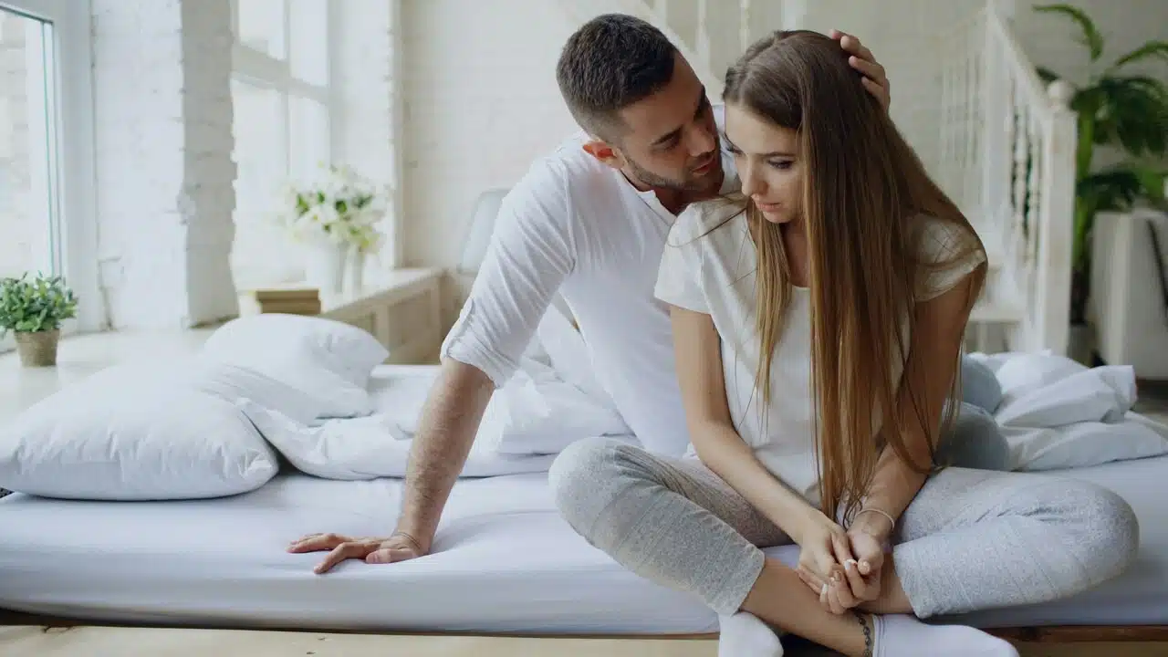 A man whispering to his wife in bed