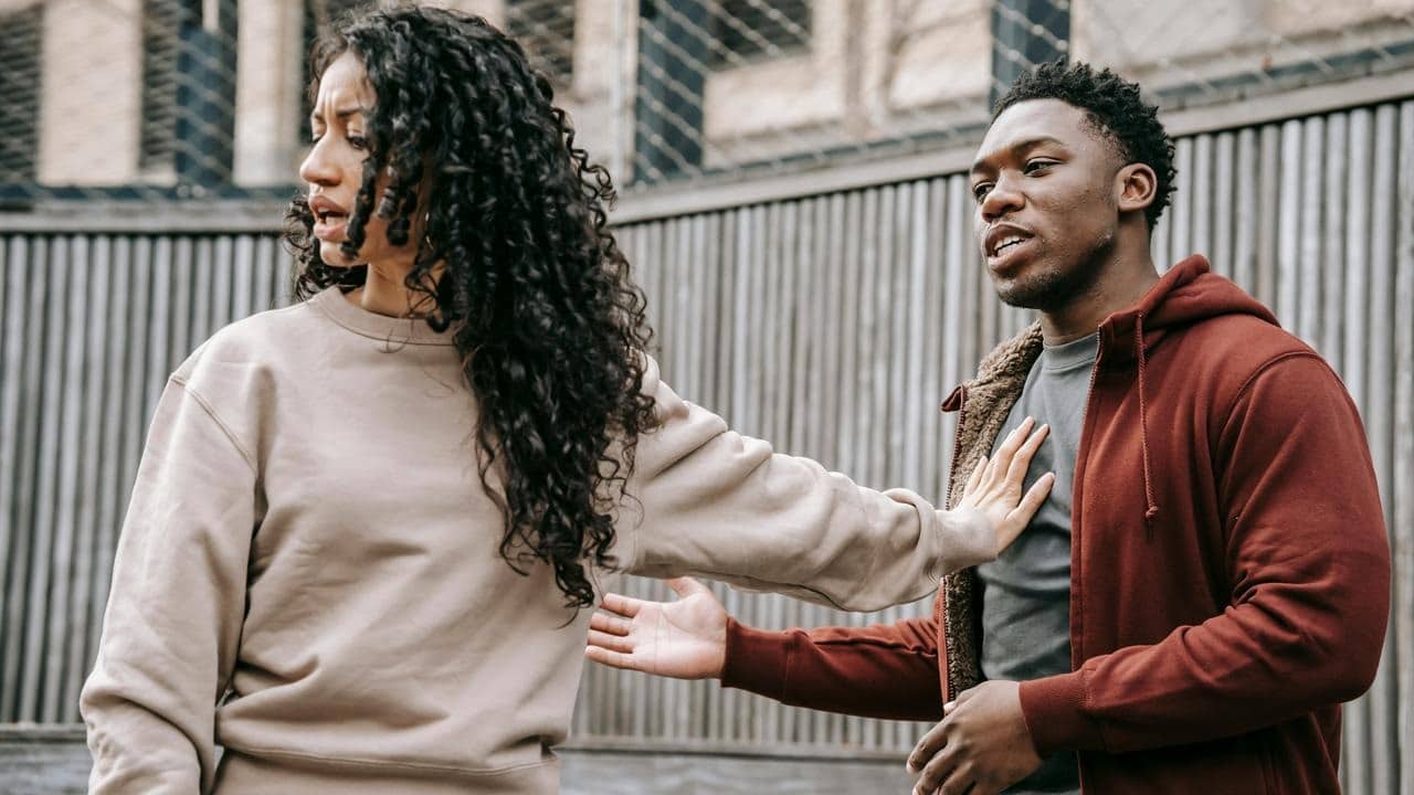 A woman pushes a man away as the man tries to explain something.