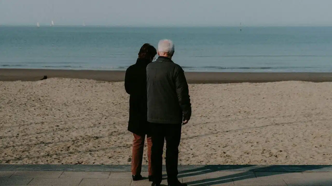 A couple standing on the beach beside the sea.