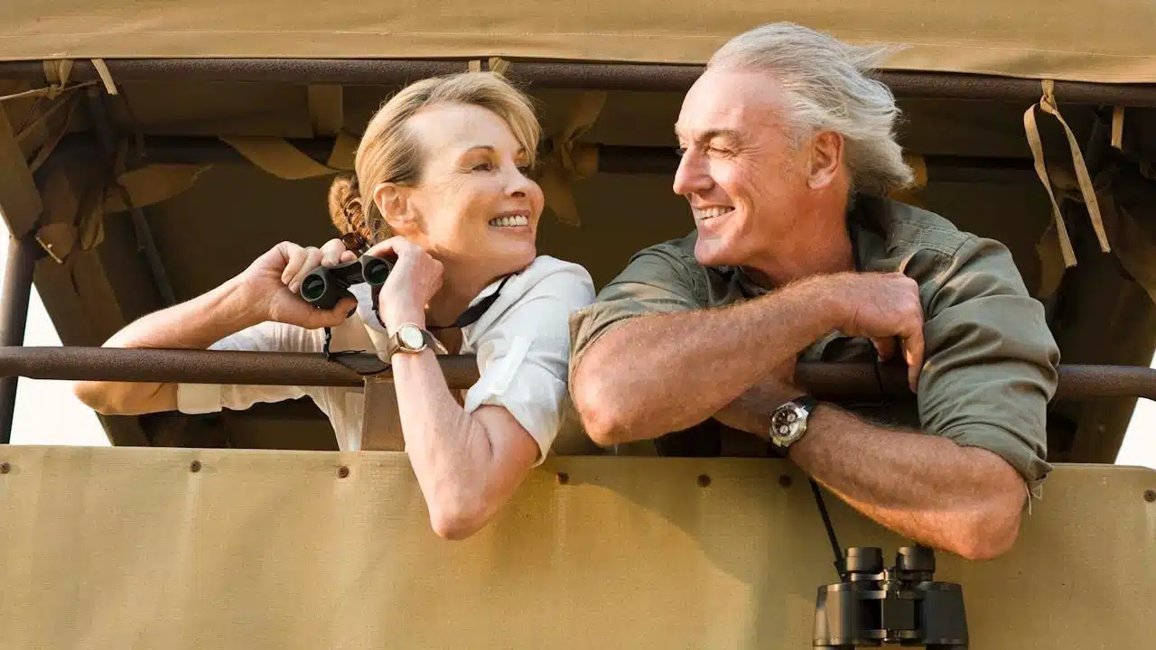 An older couple using binoculars and looking at each other.