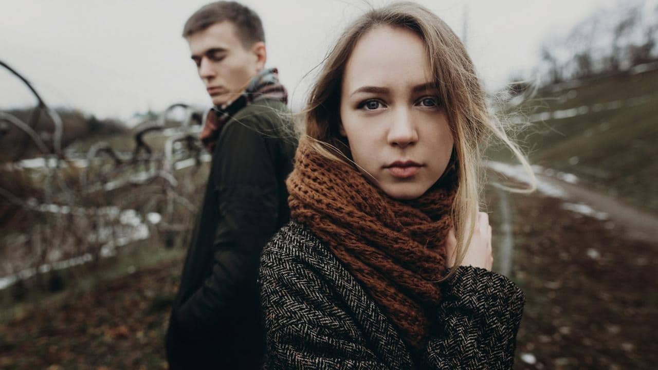 A sad couple standing outdoors.